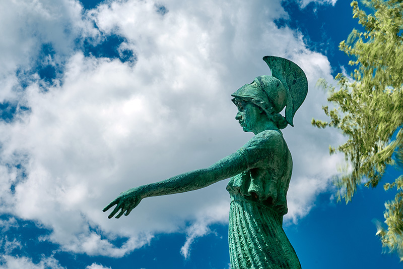 Minerva statue set against white clouds and blue sky.